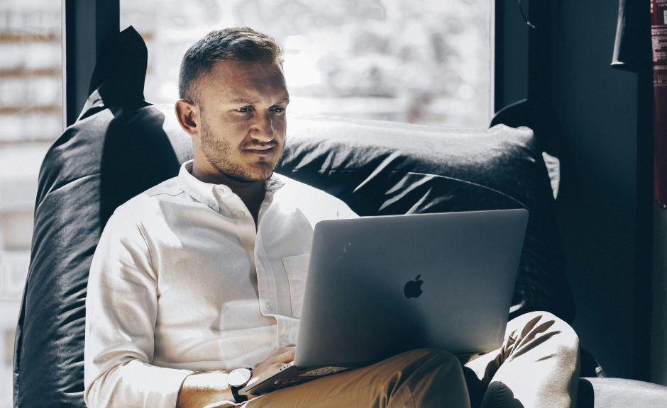 Mann sitter i sofa med PC i fanget