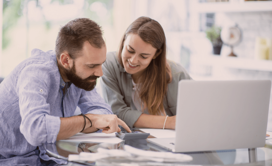 Smilende par sitter foran PC og refinansierer lån