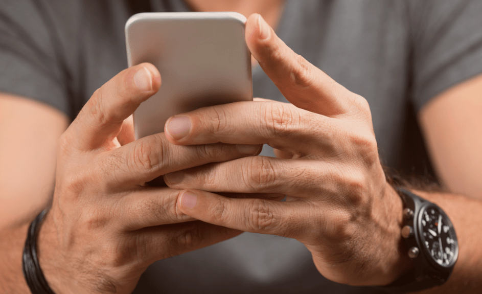 mann holder mobiltelefon i håndene