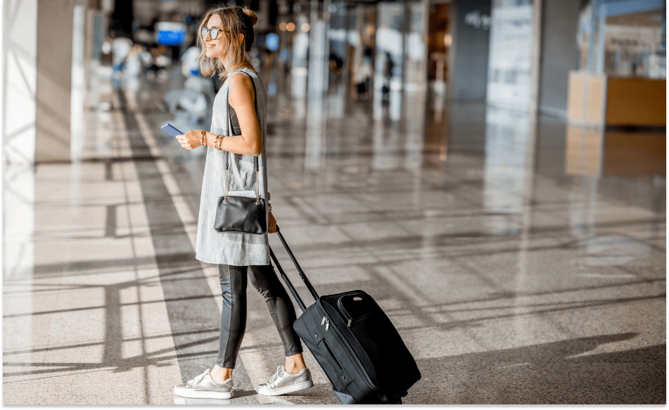 Smilende kvinne med koffert på flyplass