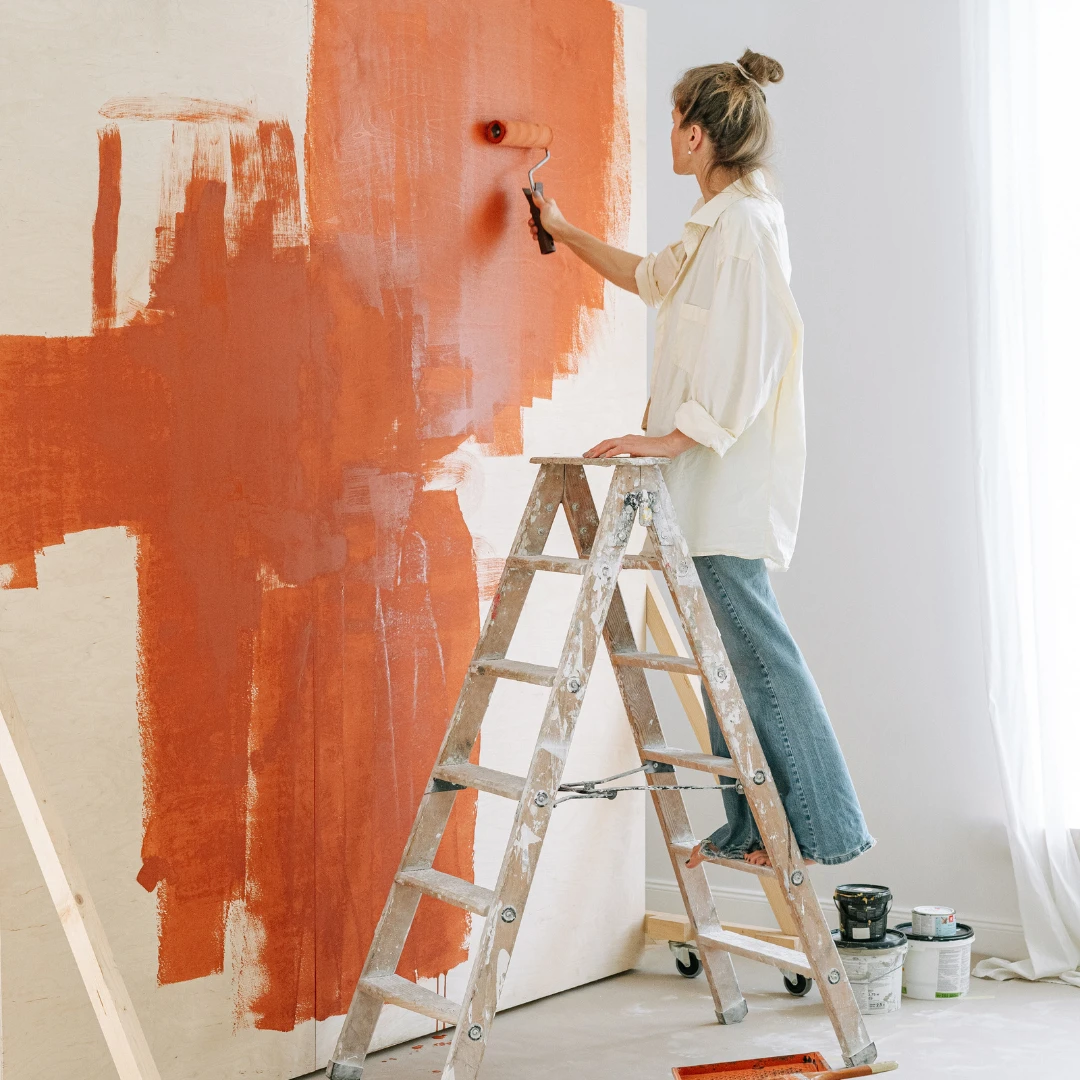 kvinne maler oransje vegg
