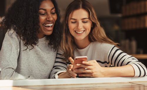 to smilende kvinner ser på mobil