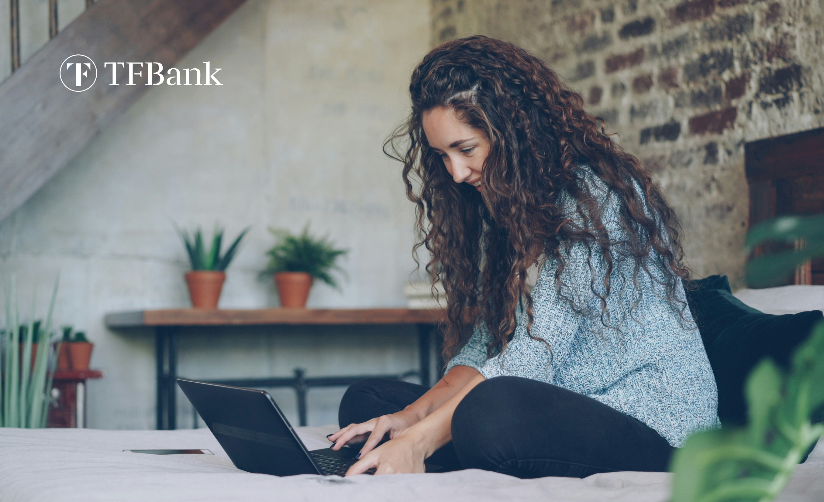 smilende jente sitter i sengen med PC