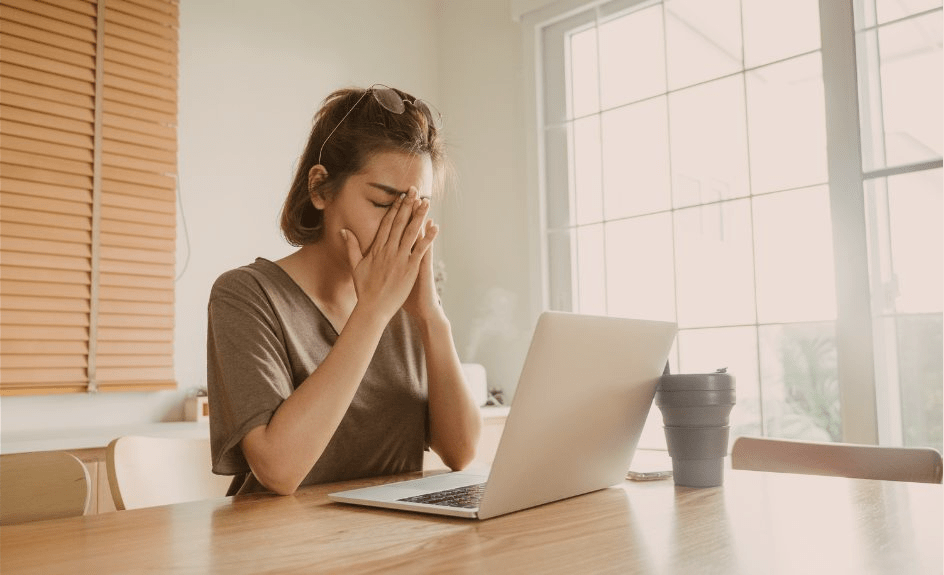 oppgitt kvinne med hendene foran ansiktet foran pc-skjerm