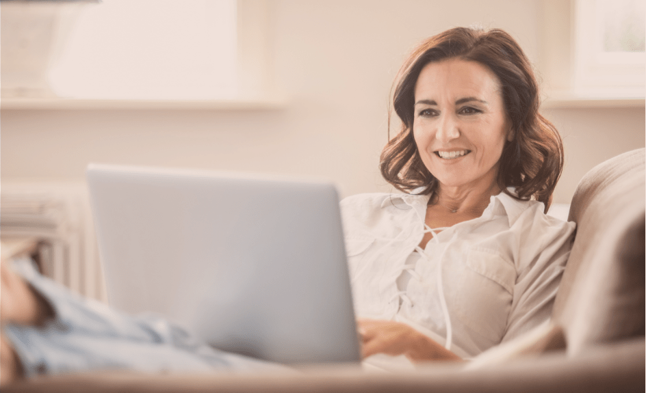 smilende kvinne sitter foran pc