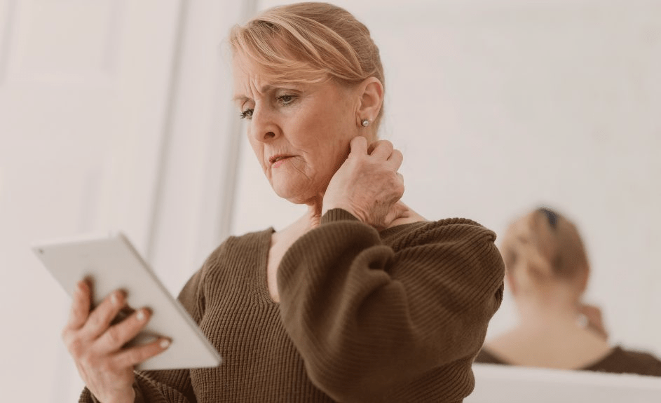 Dame ser bekymret på nettbrett og holder seg for nakken