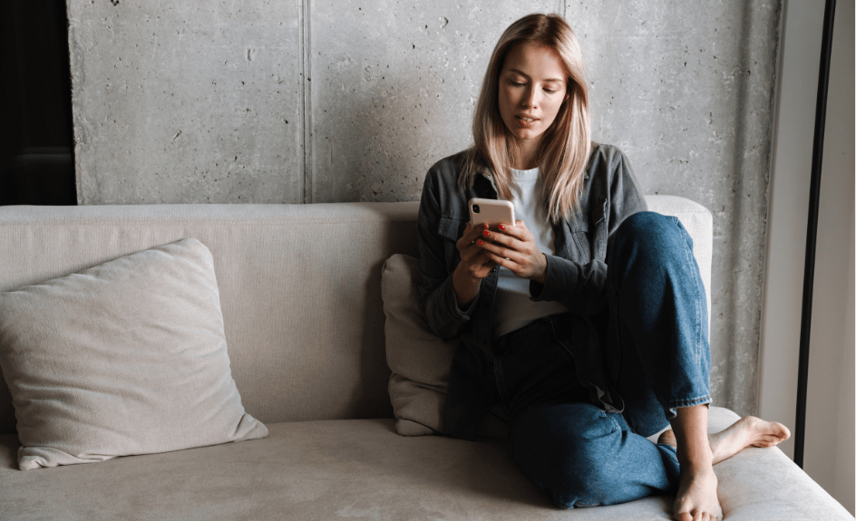 Kvinne med mobil på sofa
