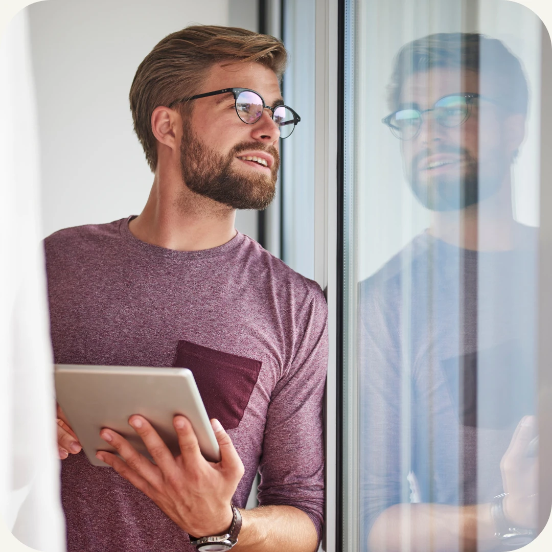 mann med nettbrett i hånden ser ut vindu