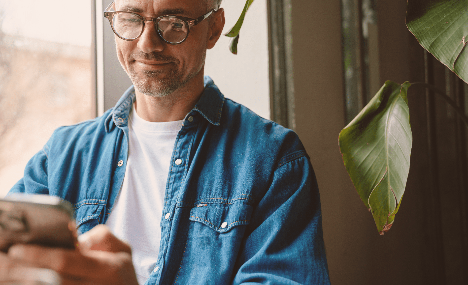 Smilende mann ser på telefon