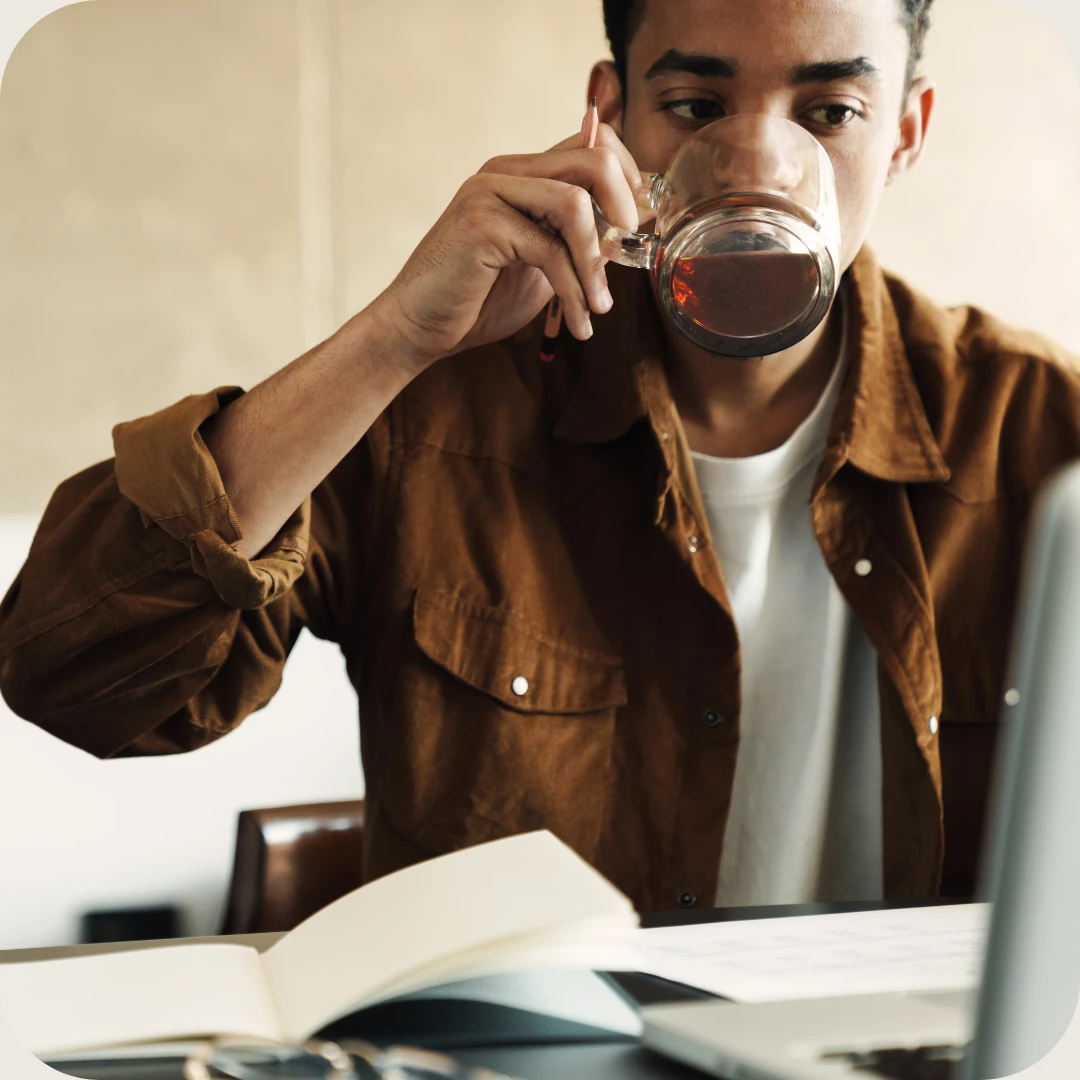 mann foran pc drikker te