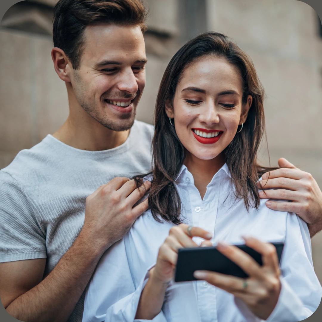 smilende kjærestepar ser på mobil